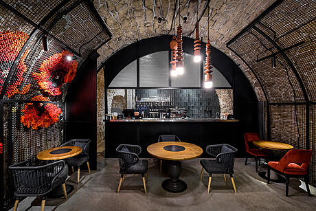 Warm, moody interior features arched stone walls, pendant lighting, and modern furnishings.