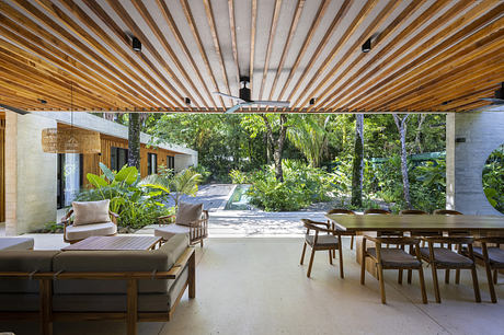 Open tropical living space with wooden ceiling and modern furniture.