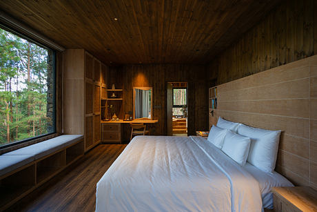 Cozy wooden bedroom with large window and forest view.