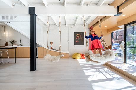 Modern open-concept interior with swings, white walls, and wood floors.