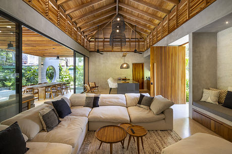 Modern living room with large sectional sofa, wooden ceiling, and glass walls.