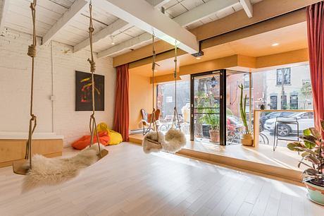Modern living room with swing chairs, large windows, and white flooring.