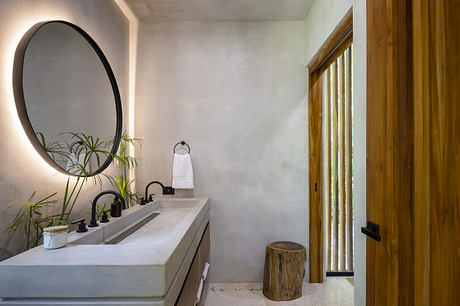 Minimalist bathroom with a concrete vanity, round mirror, and wooden accents.