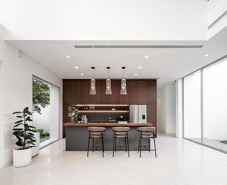 Modern kitchen with bar stools and pendant lights, wood accent, large windows, and