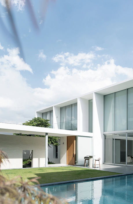 Modern white house with large windows overlooking a pool.