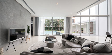 Modern living room with large windows overlooking a pool.