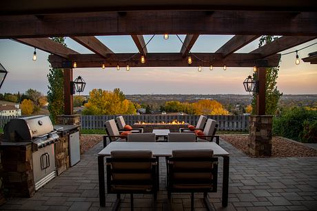 Outdoor patio with a fireplace, seating area, and grill overlooking a scenic view at