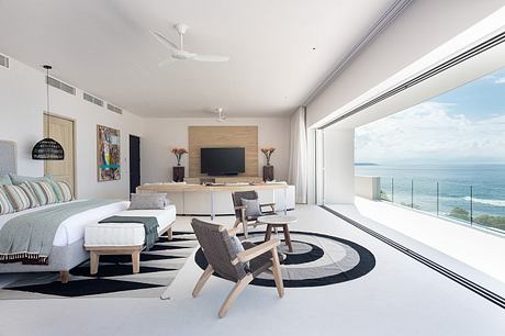 Modern bedroom with ocean view, minimalist decor, and large windows.