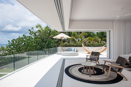 Modern terrace with hammock, chairs, and ocean view.