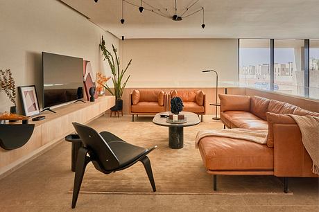 Modern living room with tan sofas, black chair, and wooden accents.