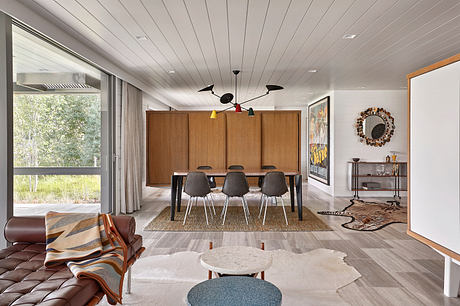 Modern living room with dining area, wooden cabinet, and stylish decor.