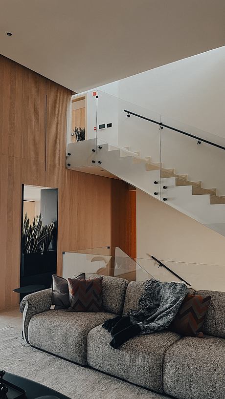 Contemporary living room with floating staircase and wood paneling.