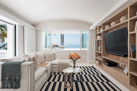 Modern living room interior with ocean view, striped rug, and built-in bookshelf