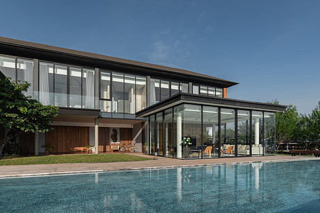 Modern house with large windows by a pool.