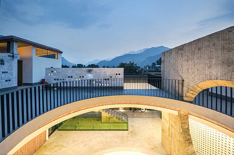 Modern courtyard with arches and warm lighting at dusk.