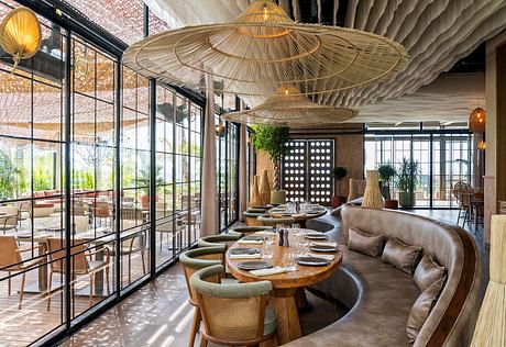 Contemporary restaurant interior with circular banquet seating and oversized pendant lighting.