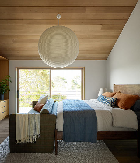 Contemporary bedroom with wooden ceiling and large pendant light.
