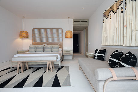 Minimalist bedroom with monochrome decor and patterned rug.