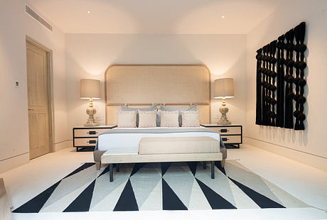 Contemporary bedroom with geometric rug and artistic wall feature.
