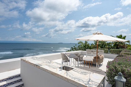 Ocean view terrace with outdoor furniture and umbrella.
