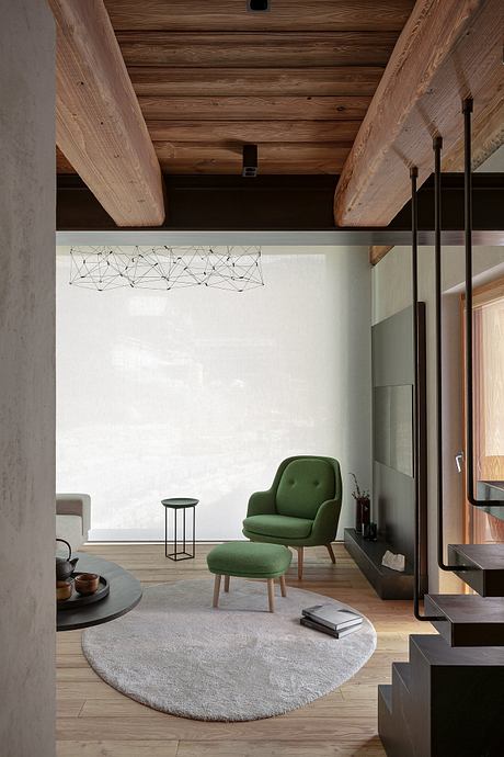 Modern living room with exposed beams, green chair, and geometric light fixture.