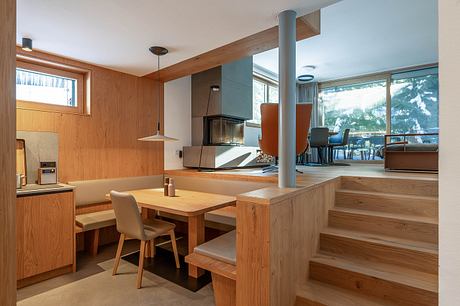 Cozy dining area with wooden walls, open floor plan, and view of snowy outdoor scenery.