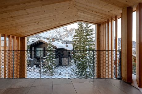 A cozy wooden cabin with a snow-covered landscape visible through the large windows.