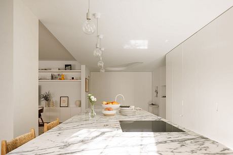 Elegant, minimalist kitchen with sleek marble countertop, pendant lights, and open shelving.