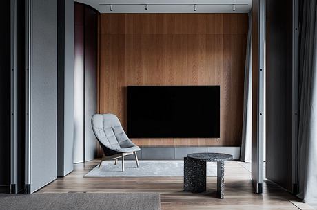 Minimalist living room with wood-paneled walls, TV display, and a modern armchair on a rug.