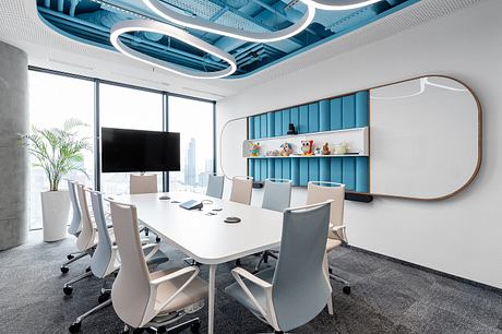 A modern, stylish meeting room with blue architectural features, a large TV, and sleek furniture.