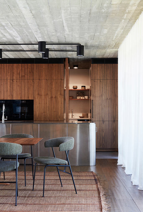 Modern kitchen with wood paneling, black lighting fixtures, and built-in shelving.