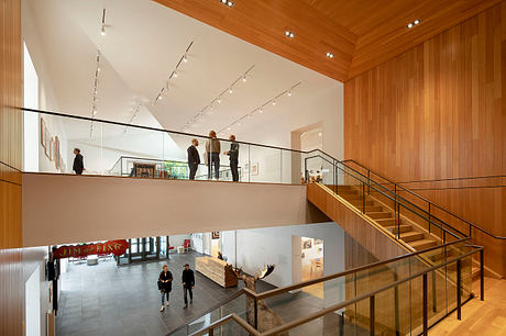 A modern, open-plan interior with wooden panels, glass railings, and track lighting.