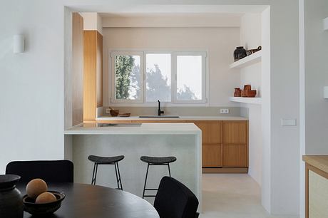 Bright, minimalist kitchen with clean lines, wood accents, and windows overlooking greenery.
