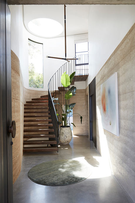 Spiral staircase, concrete walls, and lush plant decor in this modern, light-filled space.