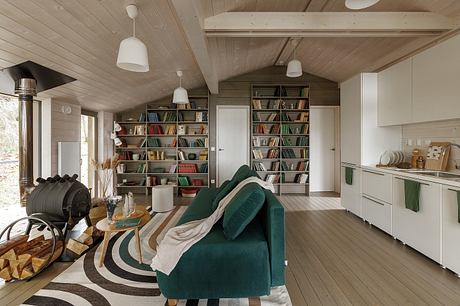 Cozy cabin interior with wooden paneled walls, bookshelves, and a green sofa.