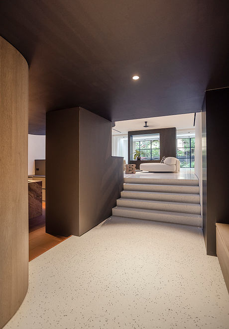 Sleek, modern interior featuring a raised platform, recessed lighting, and terrazzo flooring.