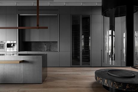 Modern kitchen with sleek black cabinetry, marble countertop, and minimalist lighting fixtures.