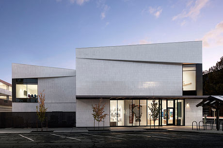 Modern two-story building with clean, angular lines and large glass panels. Minimal exterior design.