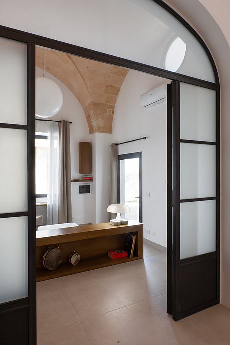 A modern, minimalist interior with wooden furnishings and stone arched ceiling.