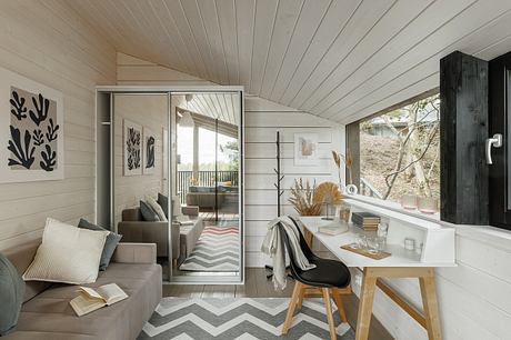 A cozy, light-filled cabin interior with a modern yet rustic aesthetic, featuring a vaulted ceiling, neutral palette, and minimalist decor.