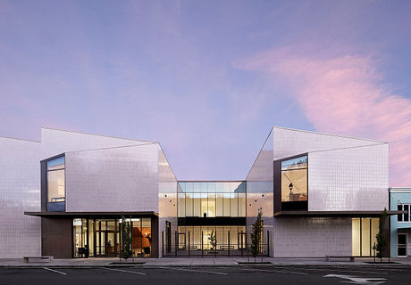 A modern, angular building with glass and metal facade, creating an inviting entrance.