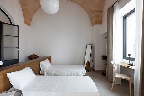 A cozy bedroom with vaulted ceilings, minimalist furnishings, and natural lighting.