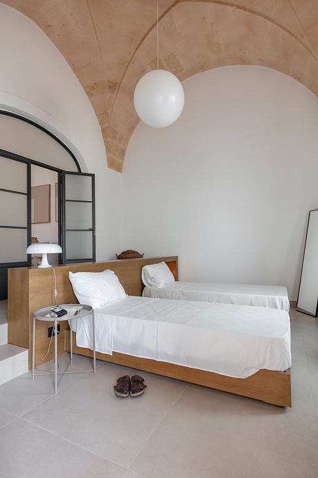 Elegant bedroom with arched ceiling, minimalist wooden furniture, and modern lighting.