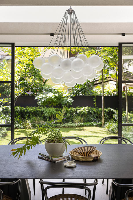 Modern dining space with large white bubble chandelier, indoor plants, and wooden decor.