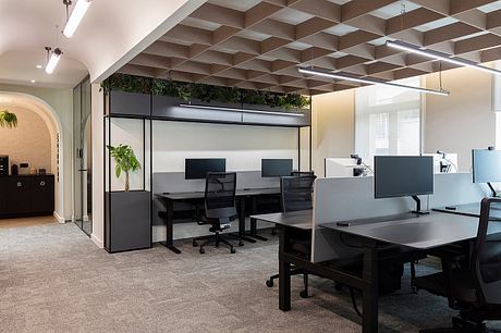 Sleek, modular office space with geometric ceiling design and lush indoor greenery.