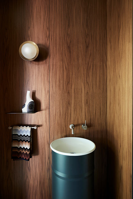 A modern bathroom design featuring a wooden wall, a cylindrical sink, and minimalist decor.