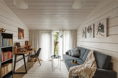 Cozy cabin interior with wooden walls, modern furniture, and abstract artworks.