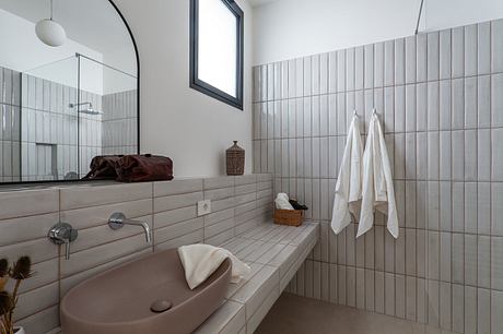 A modern bathroom with a tiled wall, minimalist vanity, and a large window providing natural light.