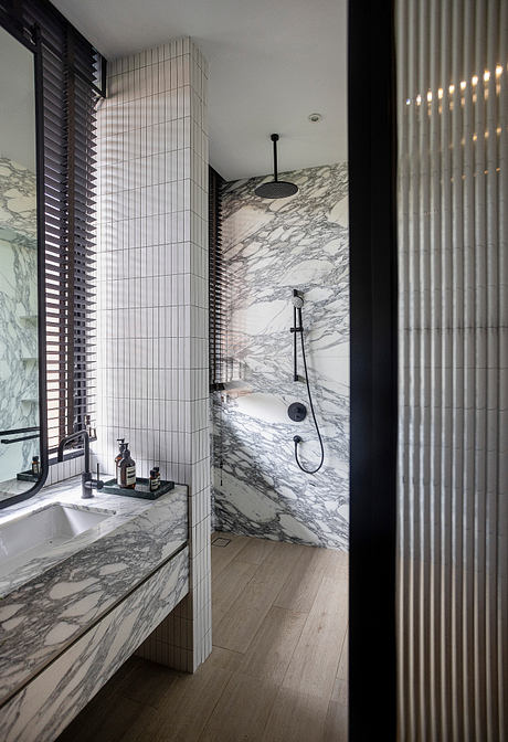 Sleek black and white bathroom with marble walls, minimalist fixtures, and wooden floor.