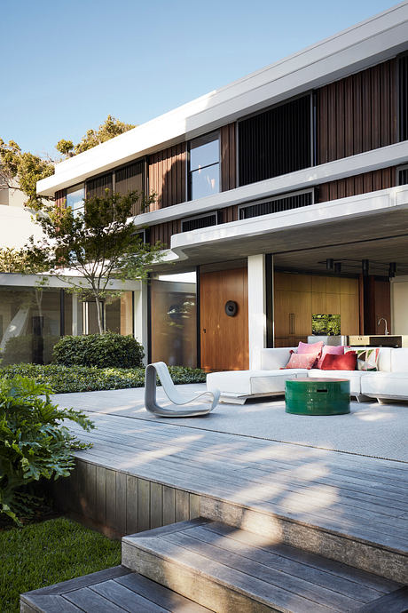 Sleek modern architecture with wooden siding, expansive windows, and a lush outdoor living space.